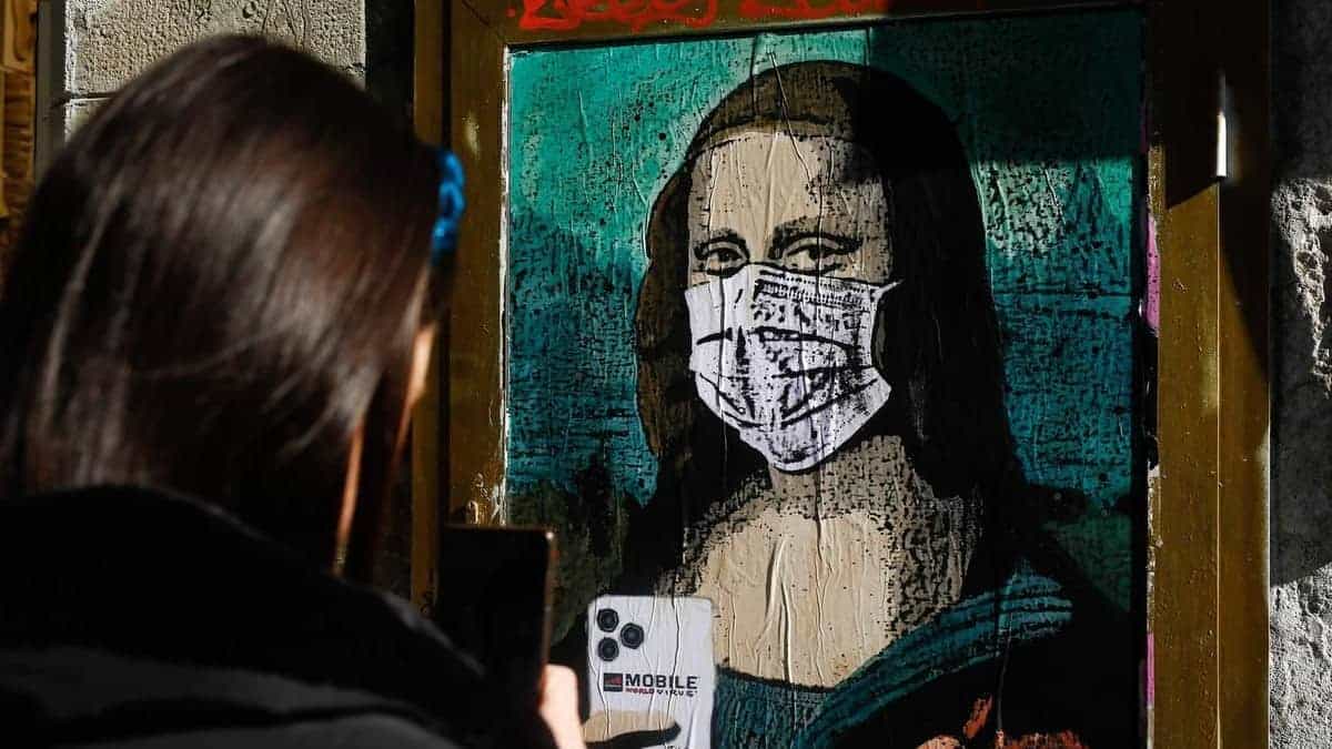 Een vrouw maakt een foto van een poster van de urban artist TVBOY in een straat van Barcelona een week nadat het World Mobile Congress werd geannuleerd.